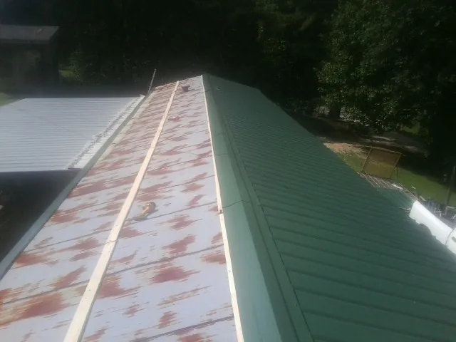 Old rusted panels beside newly installed green metal roofing — Wind Damage Roof Repair by Roofing Brothers in Peterborough