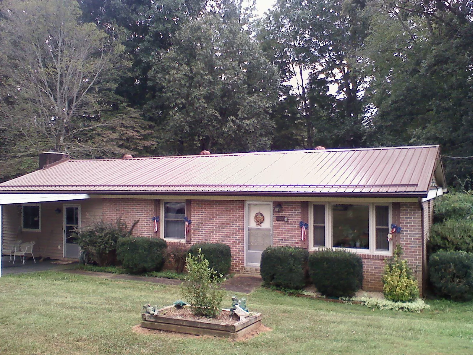 Bronze metal roof on a brick ranch home with a carport in Peterborough