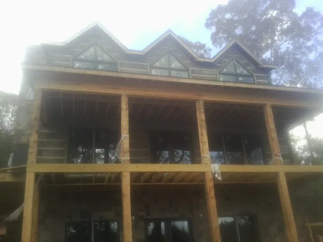 Dormers and porch framing on a large log home under construction — Roof Coating work by our crew in Peterborough
