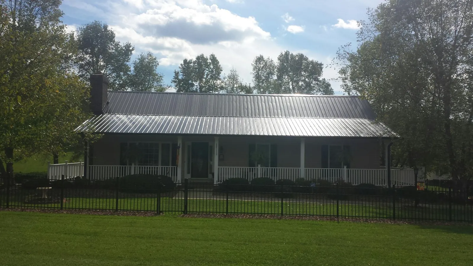 Gray metal roof on a brick ranch with a full width front porch — Gutter Guard Installation work by our crew in Peterborough