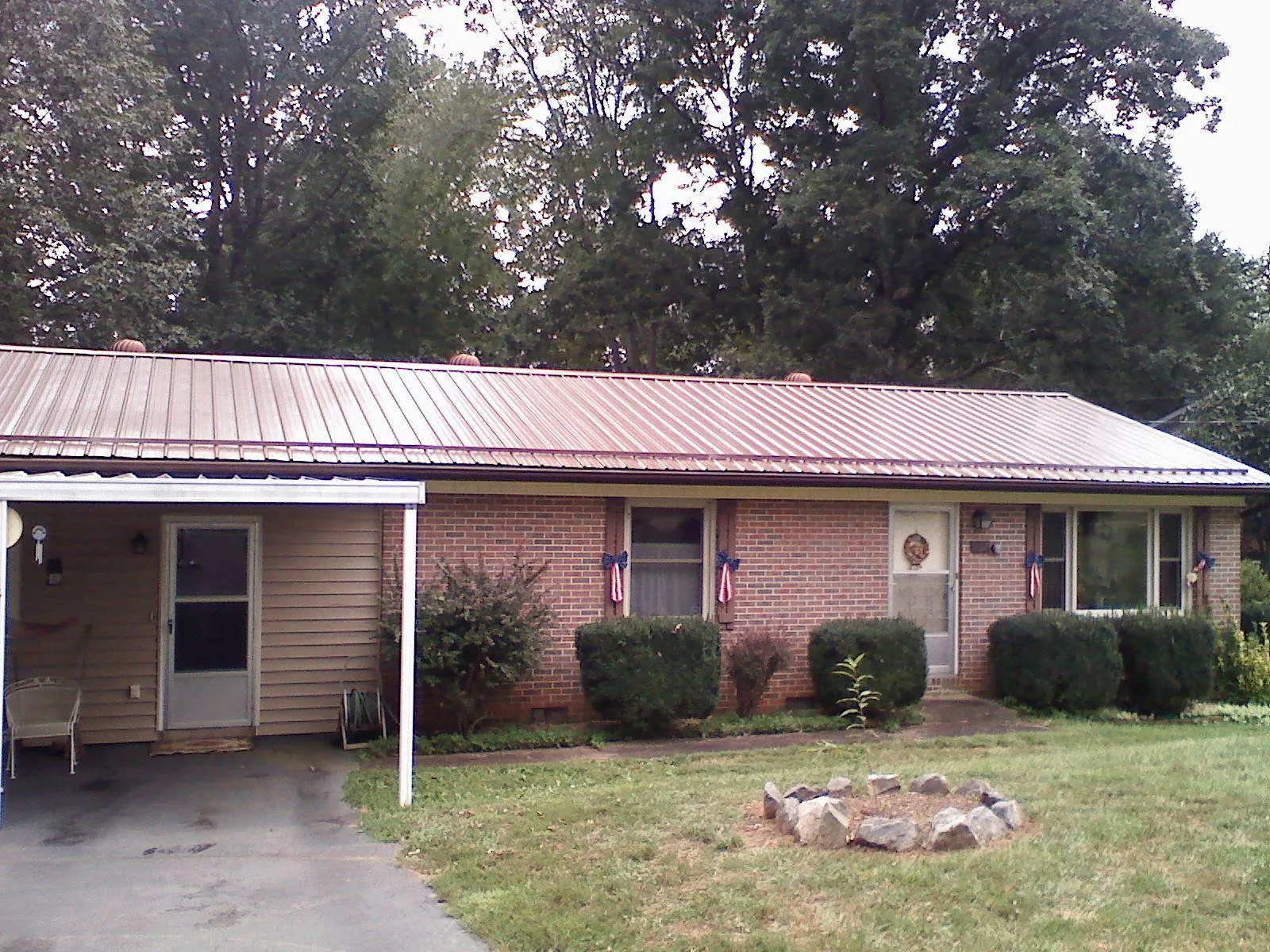 Bronze metal roof and carport on a brick ranch home — Roof Repair work by our crew in Peterborough