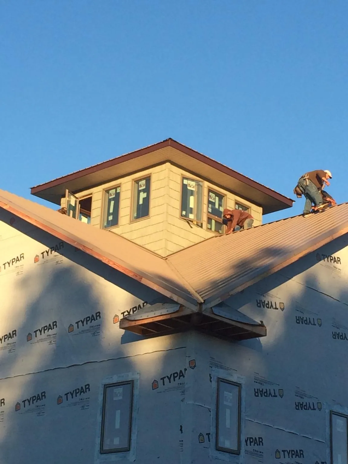Roofers working around a rooftop cupola on a new metal roof at sunset — Roof Waterproofing in Peterborough by Roofing Brothers